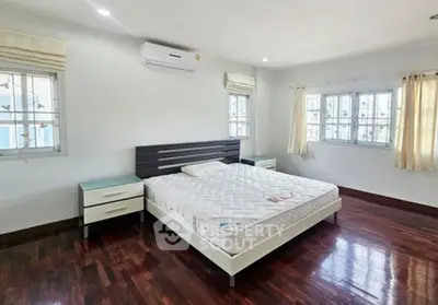 Spacious bedroom with hardwood floors and natural light from large windows.