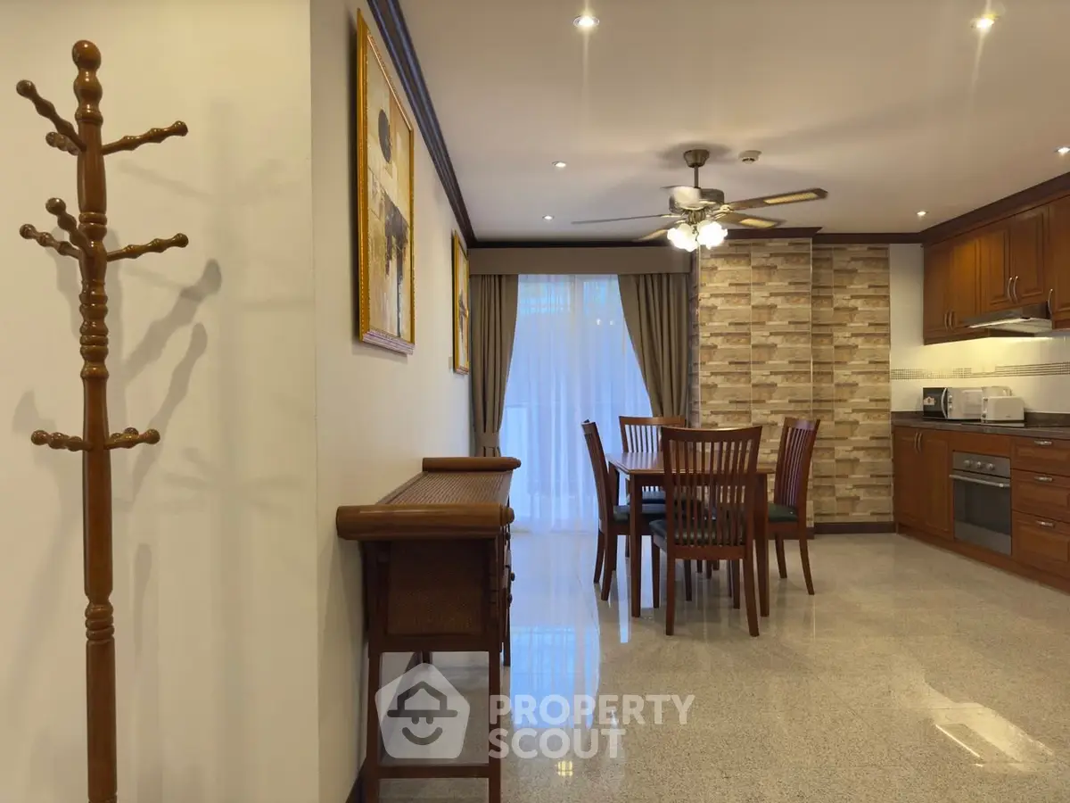 Elegant dining area with stone accent wall and modern kitchen in open layout apartment.