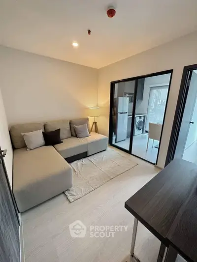 Modern living room with cozy sofa and open kitchen layout in stylish apartment.
