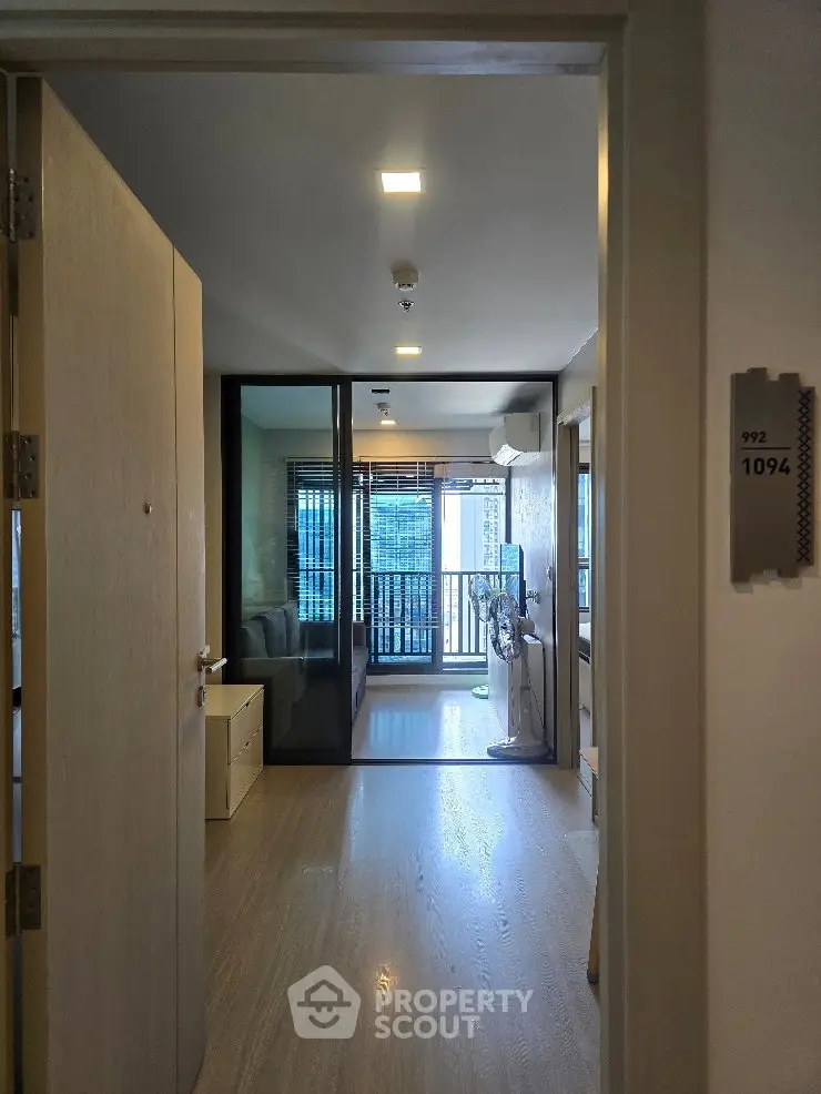 Modern apartment entrance with glass doors leading to a bright living area and balcony view.