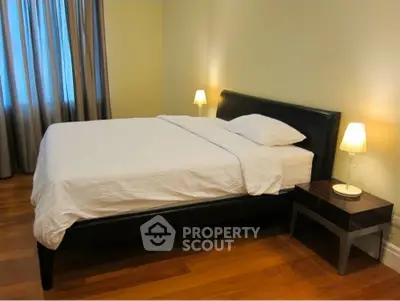 Cozy bedroom with elegant wooden flooring and modern bedside lamps.