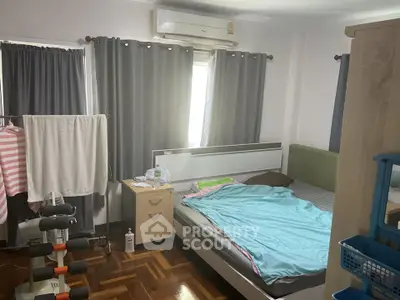 Cozy bedroom with air conditioning and natural light, featuring a comfortable bed and stylish curtains.