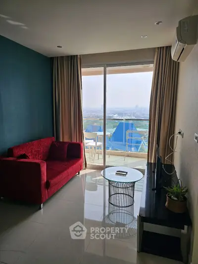 Modern living room with stunning city view, red sofa, and balcony access in a high-rise apartment.