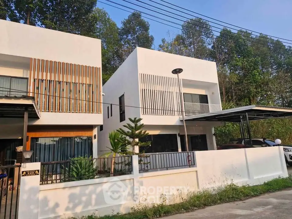 Modern white two-story houses with sleek design and lush greenery in a serene neighborhood.