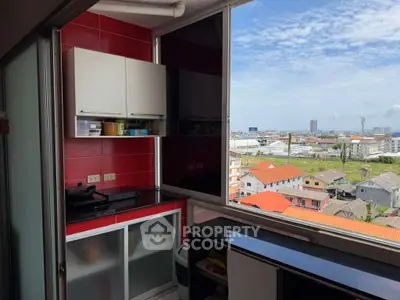 Compact kitchen with vibrant red backsplash and stunning city view from high-rise apartment.