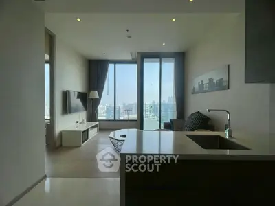 Modern living room with city view, open layout, and sleek furnishings in high-rise apartment.