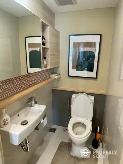 Modern bathroom with stylish decor and compact design featuring a wall-mounted sink and framed artwork.