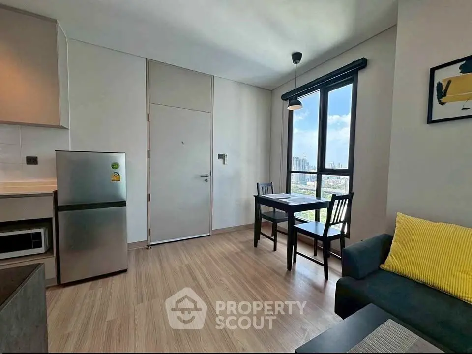 Modern apartment interior with dining area and city view, featuring sleek furniture and natural light.