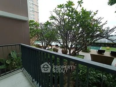 Charming balcony view overlooking lush garden and pool area in modern apartment complex.