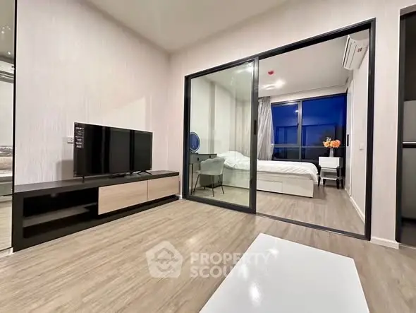 Modern apartment with open living room and bedroom, featuring sleek design and large glass partition.