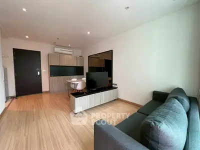Modern living room with sleek furniture and wooden flooring, featuring a cozy sofa and entertainment unit.