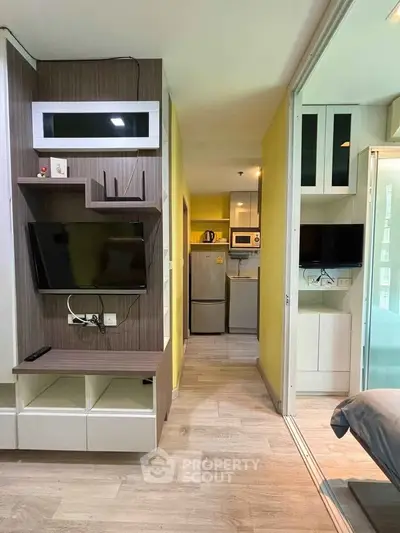 Modern apartment interior with open layout, featuring a cozy living area and compact kitchen with appliances.