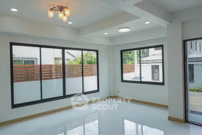 Spacious modern living room with large windows and elegant lighting in a contemporary home.