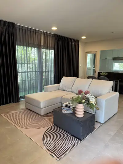 Modern living room with stylish sofa and elegant decor, featuring large windows and chic curtains.