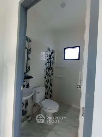 Modern bathroom with geometric tile design and compact layout.