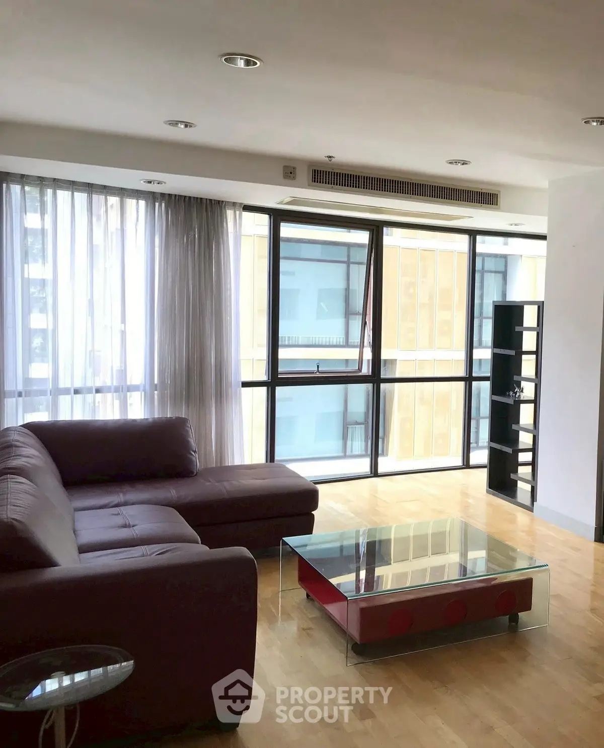 Spacious living room with modern furniture and large windows in a city apartment.