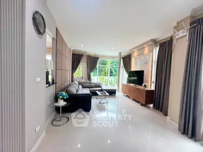 Spacious modern living room with elegant decor and large windows offering lush garden views.