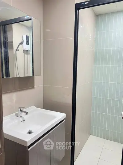 Modern bathroom with sleek sink and shower area in contemporary apartment.