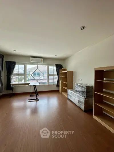 Spacious room with large windows and wooden flooring, ideal for versatile use.