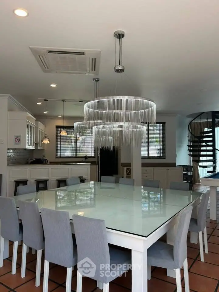 Elegant dining area with modern chandelier and spiral staircase in a spacious kitchen.