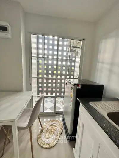 Compact kitchen with modern appliances and natural light through grid window.