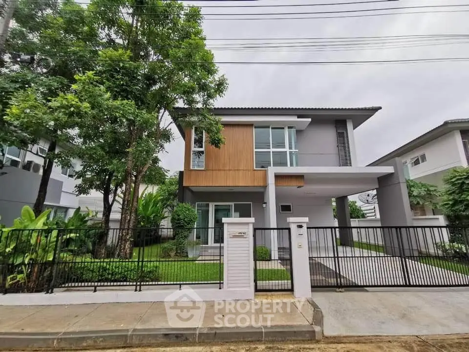 Modern two-story house with sleek design and lush greenery in suburban neighborhood.