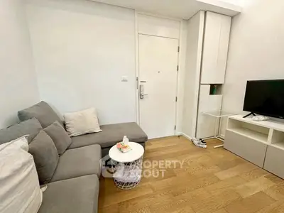 Cozy living room with modern gray sofa and sleek TV setup on wooden flooring.