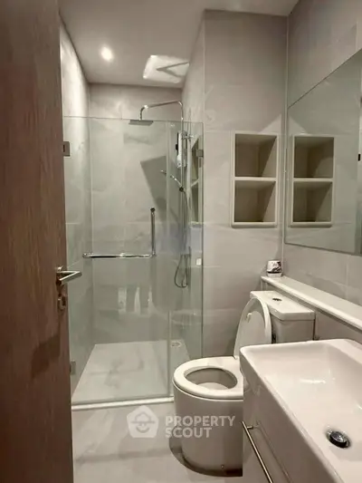 Modern bathroom with glass shower and sleek fixtures in a contemporary apartment.