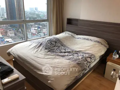 Cozy bedroom with city view, featuring a stylish bed and large window for natural light.