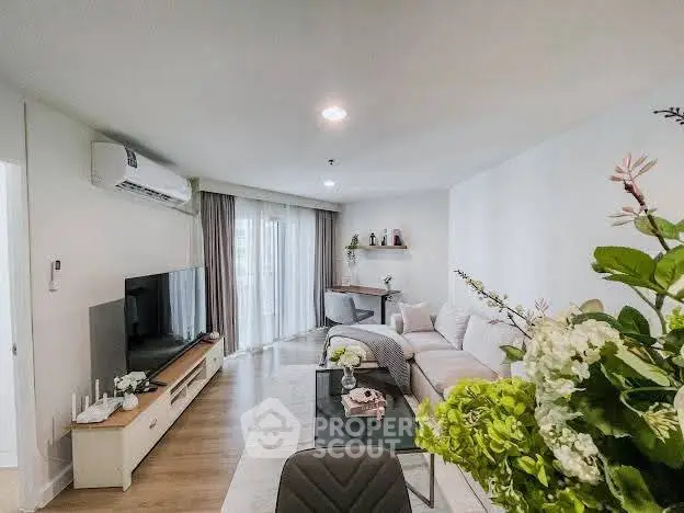 Modern living room with stylish decor, large TV, and cozy seating area in a bright apartment.