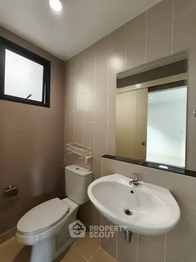 Modern bathroom with sleek fixtures and neutral tiles, featuring a large mirror and natural light.