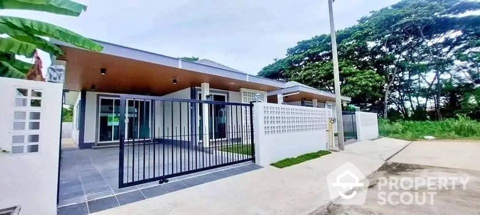 Modern single-story house with gated entrance and lush surroundings