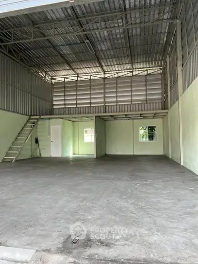 Spacious industrial-style warehouse with mezzanine and high ceilings, ideal for storage or workshop.
