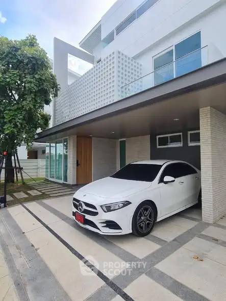 Modern luxury home with sleek car parked in driveway, showcasing contemporary architecture and design.
