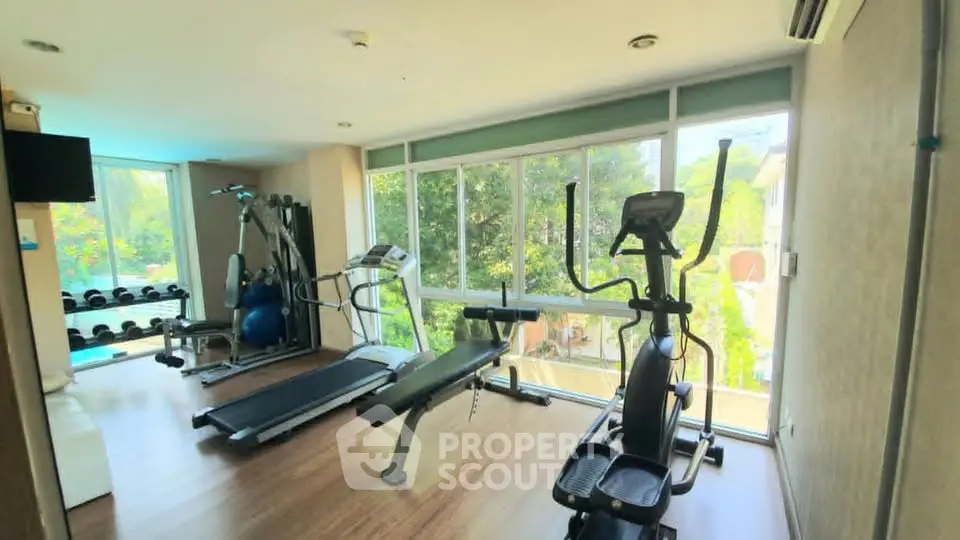 Modern gym with exercise equipment and large windows offering a scenic view.