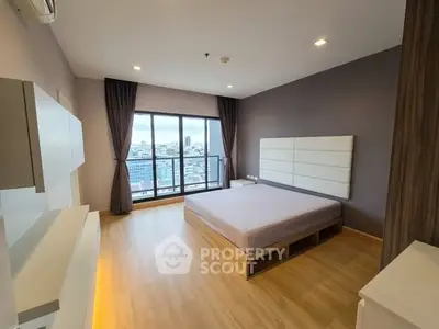Spacious modern bedroom with large windows offering stunning city views, featuring sleek wooden flooring and elegant decor.