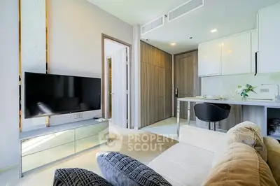 Modern living room with sleek design and open kitchen layout, featuring a large TV and stylish furniture.
