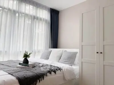 Cozy bedroom with natural light and modern decor, featuring a stylish bed and wardrobe.