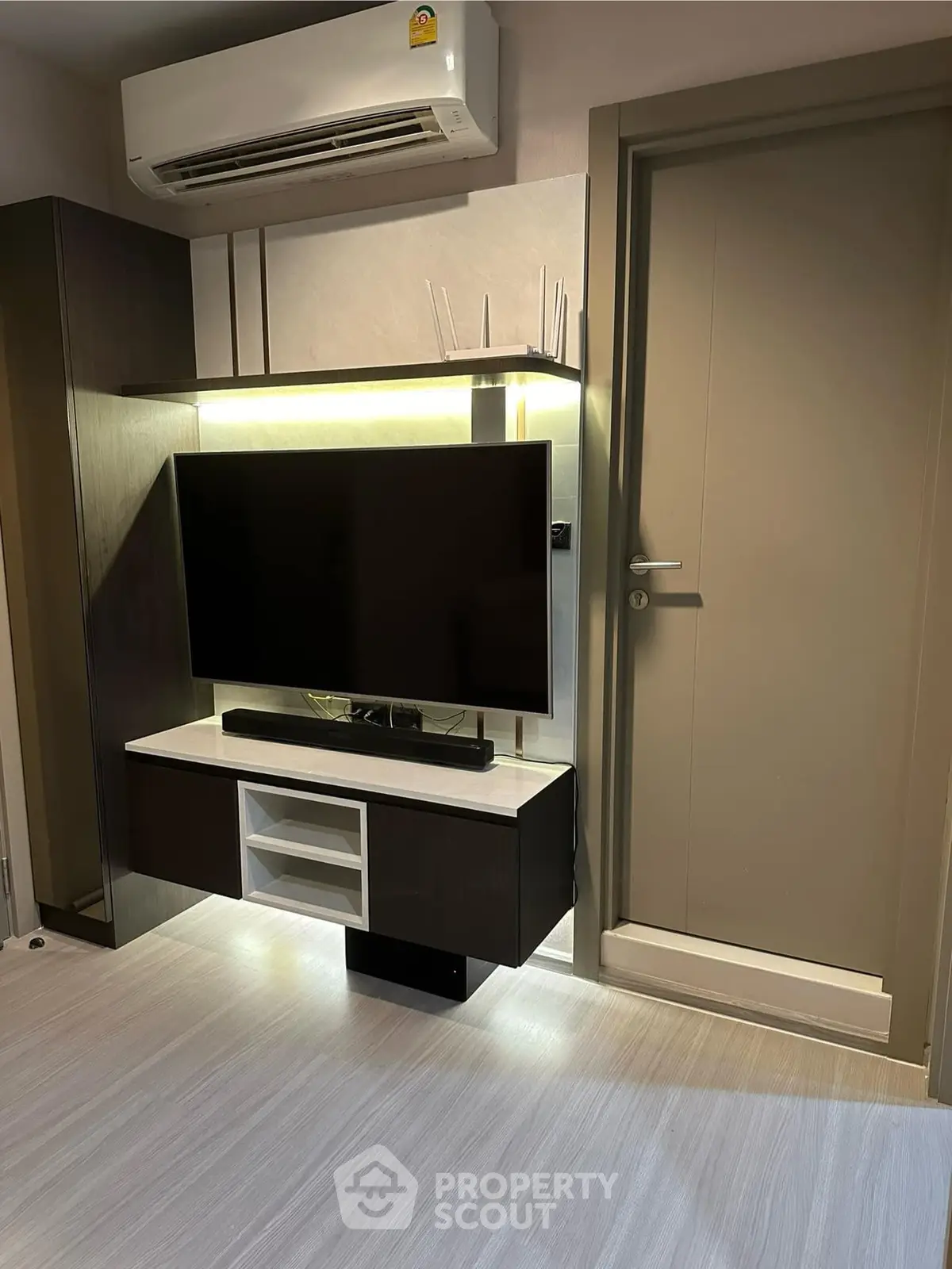Modern living room with sleek TV setup and air conditioning unit.