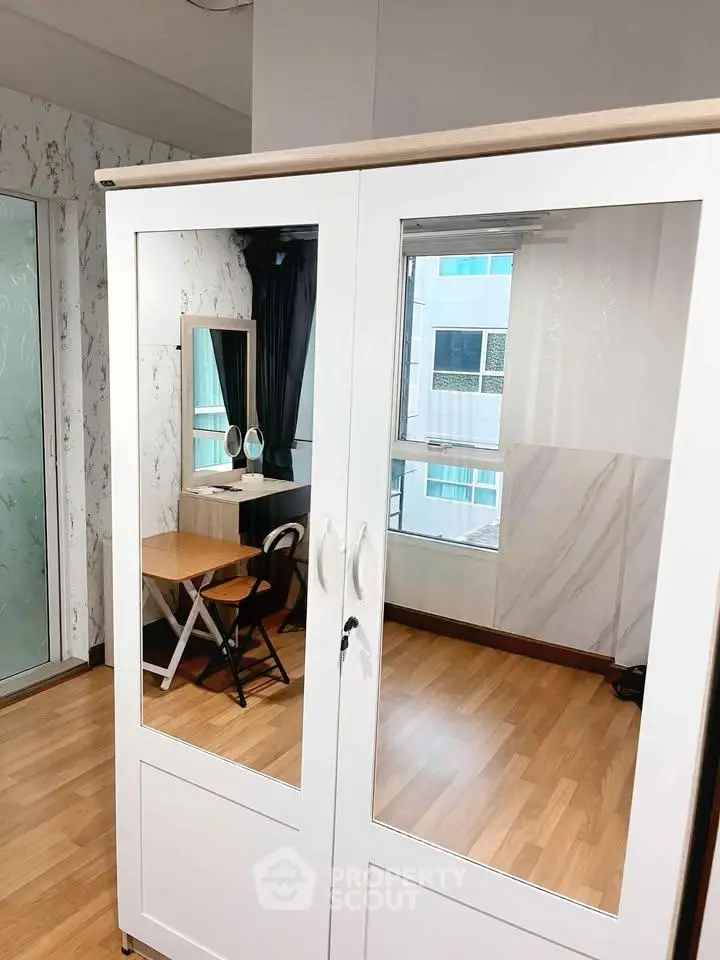 Modern bedroom with mirrored wardrobe and stylish vanity set near window.