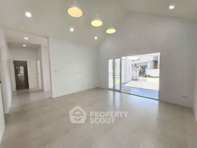 Spacious modern living room with high ceiling and large windows offering natural light.
