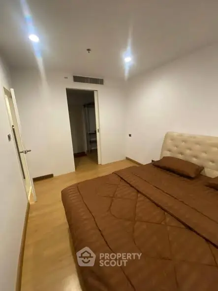 Spacious bedroom with modern decor and wooden flooring in a cozy apartment.