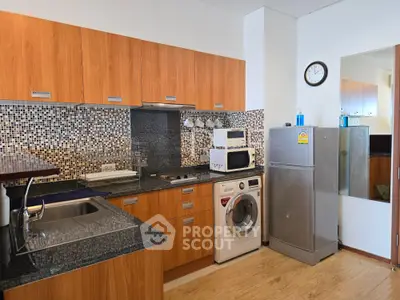 Modern kitchen with wooden cabinets, granite countertops, and built-in appliances including washing machine and fridge.