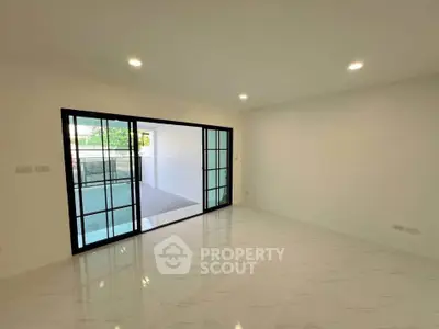 Spacious modern living room with sliding glass doors and elegant white flooring.