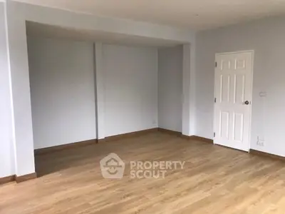 Spacious empty room with wooden flooring and white walls, ready for customization.