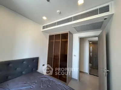 Modern bedroom with built-in wardrobe and ensuite bathroom in a stylish apartment.