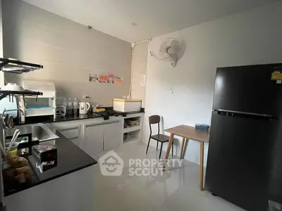 Modern kitchen with sleek black countertops and essential appliances in a cozy apartment setting.