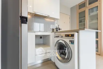 Modern kitchen with sleek appliances and washing machine in compact layout.
