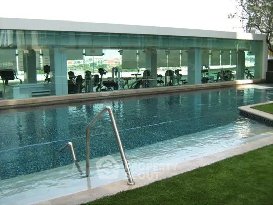 Luxurious swimming pool with modern gym view in upscale residential complex.