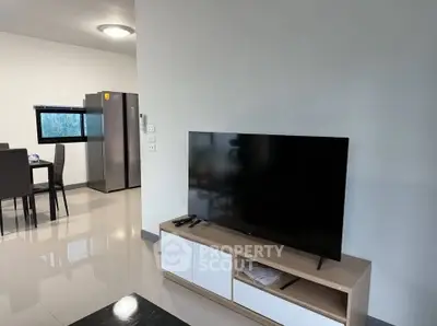 Modern living room with sleek TV and dining area, featuring a contemporary fridge and minimalist design.